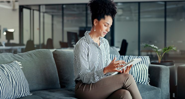 Woman on an office sofa reading a tablet
