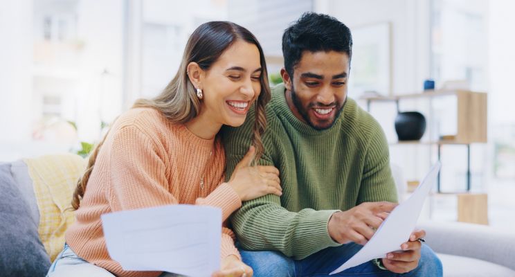 Young couple smiling over paperwork on the couch