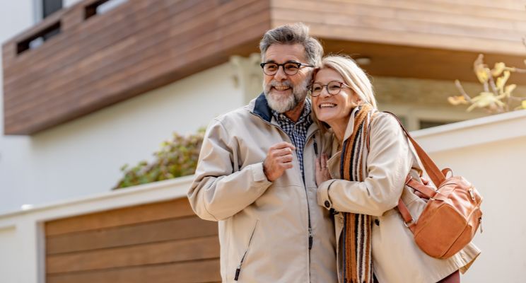 Smiling older couple embracing outside a modern vacation home
