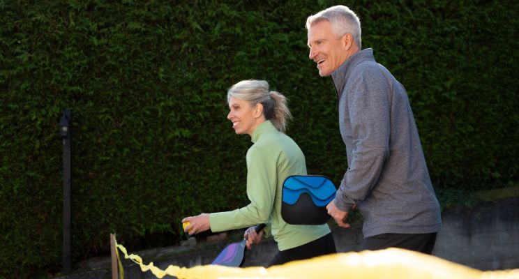 Older couple playing pickleball outdoors