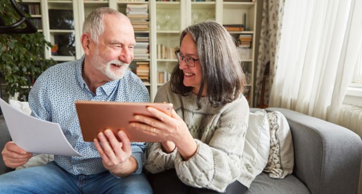 Smiling older couple looking at a tablet together on the sofa