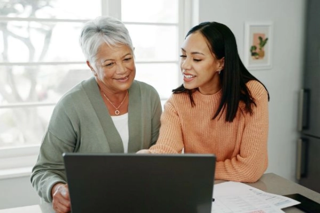 Woman showing her grandmother something on a laptop at home