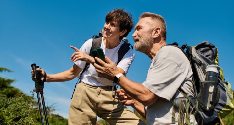 Retired couple on a hike, pointing at a view with a phone in hand