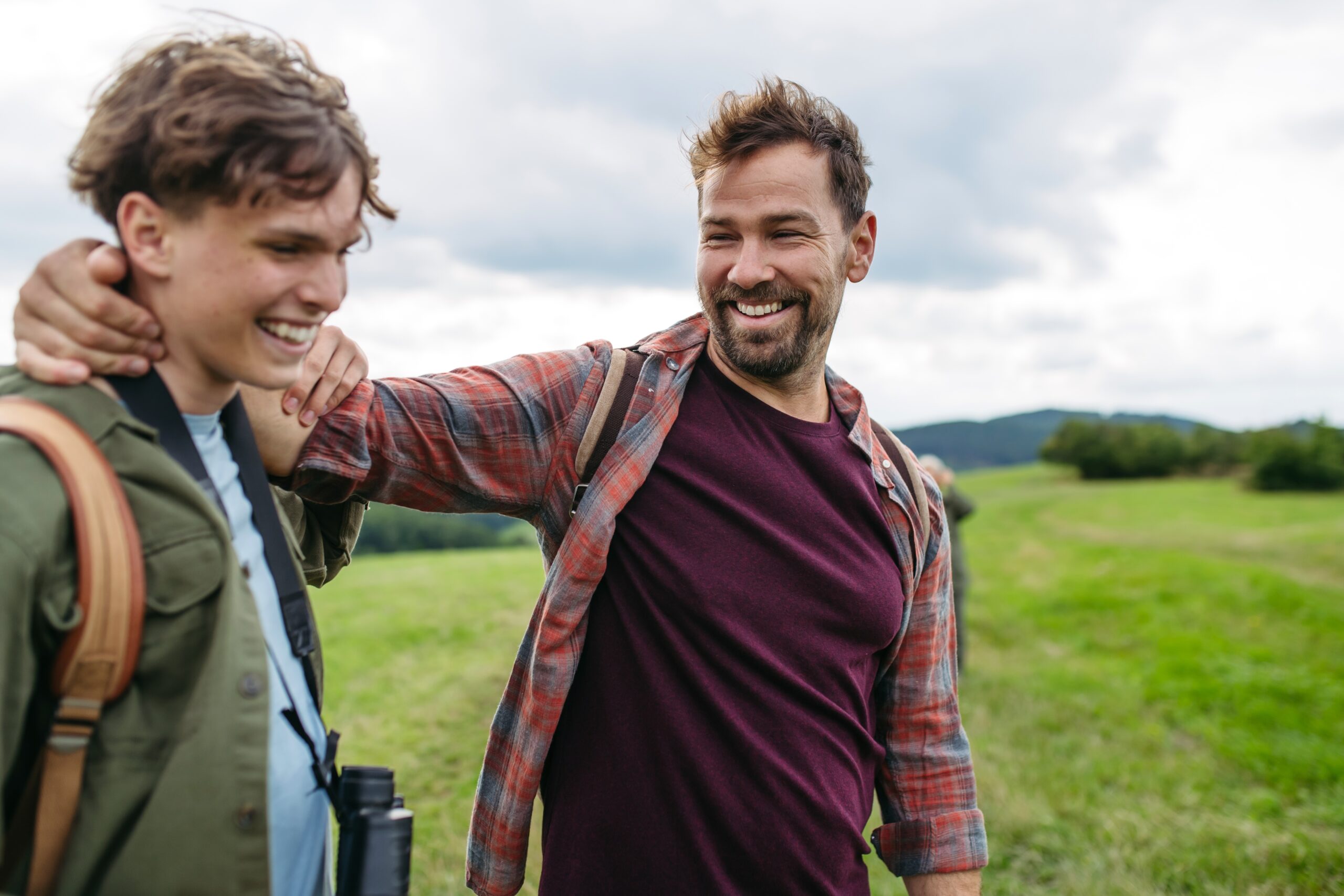 Father with his arm around his teenage son on a countryside hike